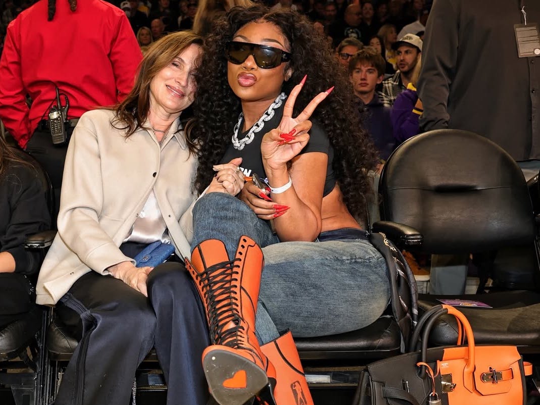 Megan Thee Stallion Courtside com salto laranja com cadarço e uma bolsa Hermès Casaque HAC preta e Feu no jogo Mavs vs.